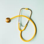 Top view of yellow medical stethoscope placed on white surface during coronavirus pandemic
